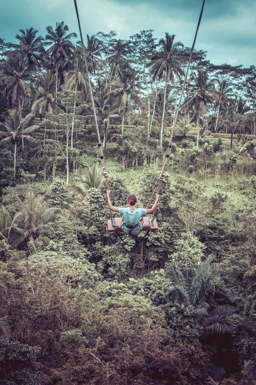 woman sitting on wood plank in zip line