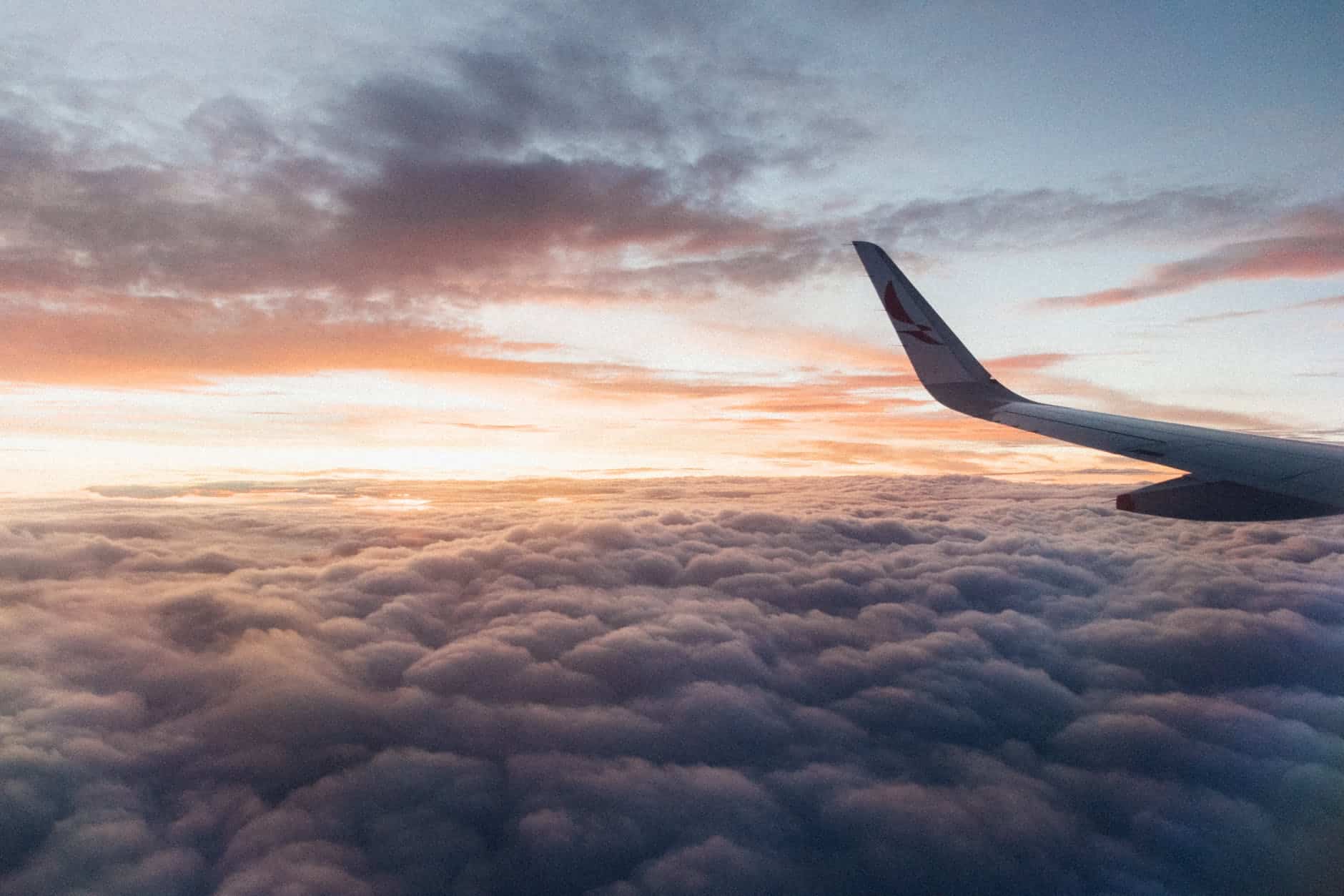 white airliner wing on top of sea clouds