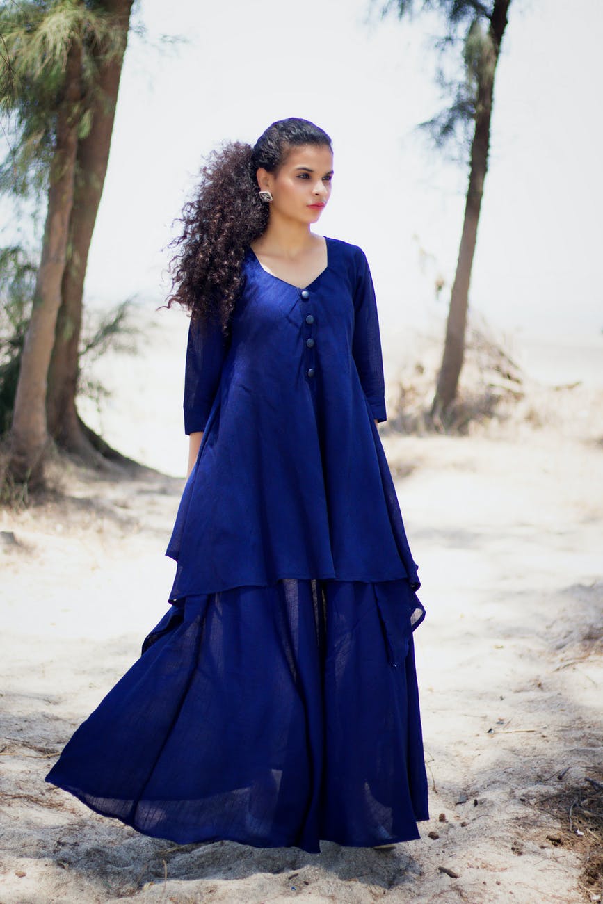 woman wearing blue dress standing on seashore