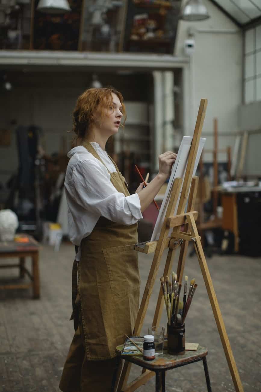 young woman in brown apron sketching on white cardboard