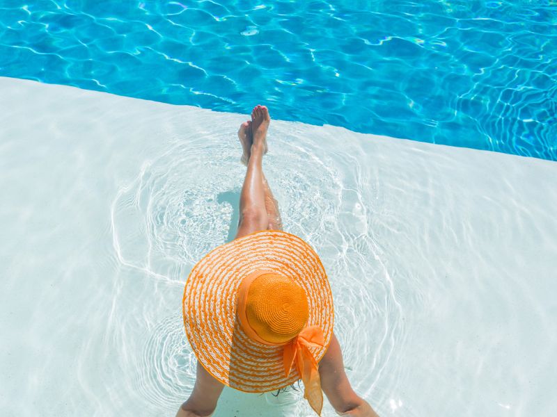 Woman wearing a sunhat relaxing by pool